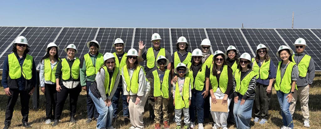 Group of students and MCE staff standing in front of solar panels at MCE's Solar One in Richmond, California.
