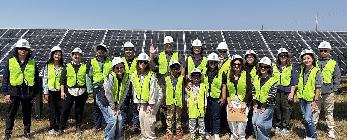 Group of students and MCE staff standing in front of solar panels at MCE's Solar One in Richmond, California.