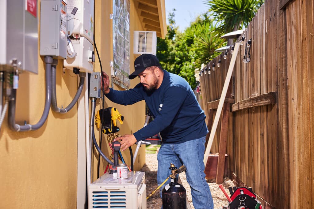 Photo of a trade person installing a heat pump.