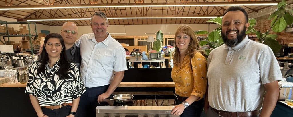 MCE staff pose in front of an induction stove.