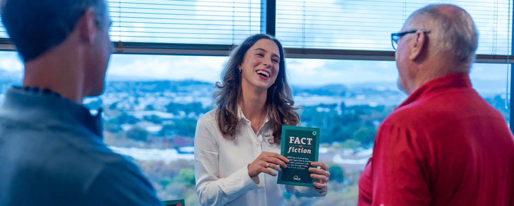 A woman laughing while holding a game card that reads fact or fiction.